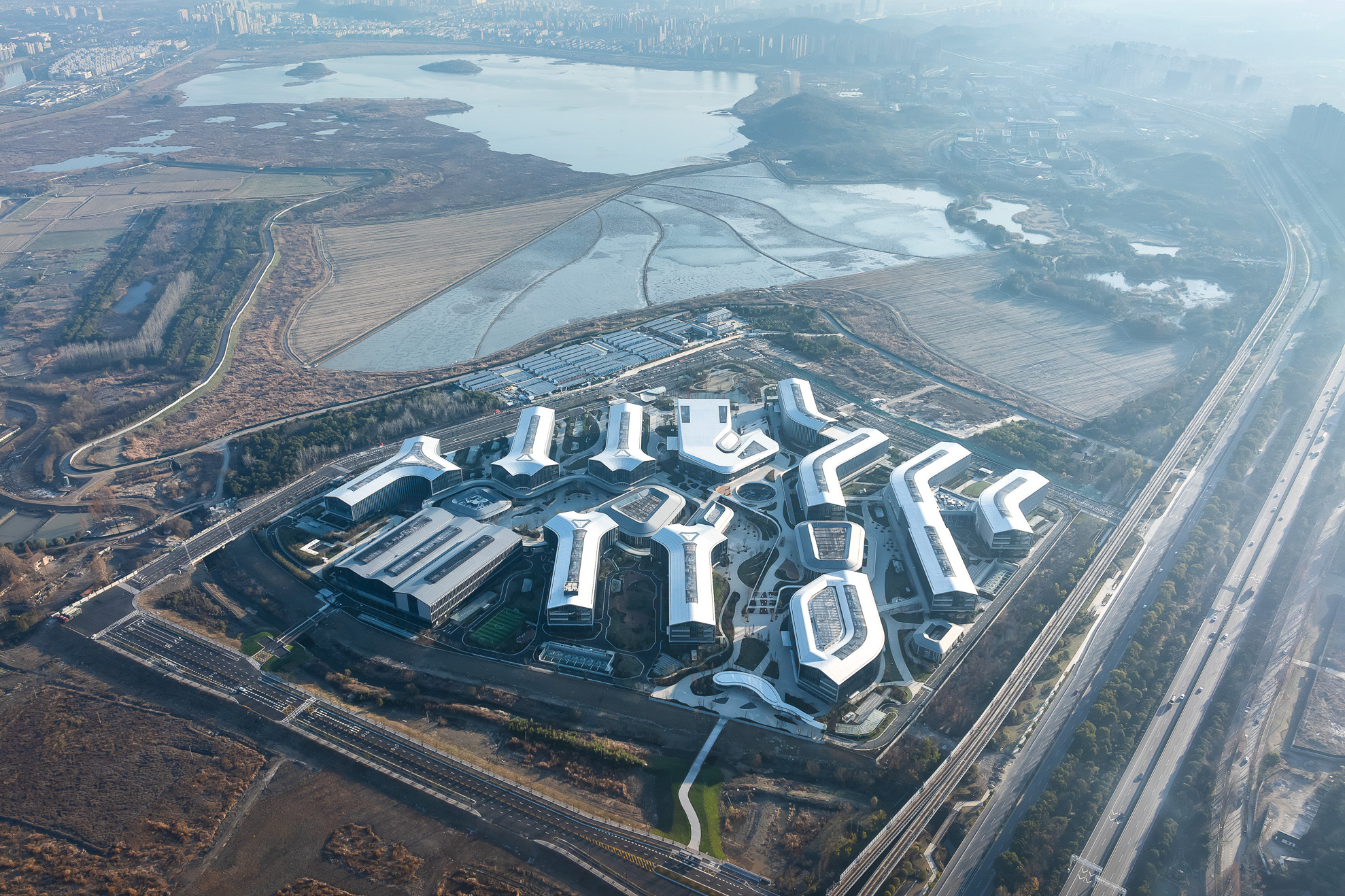 園區以菩提葉脈為靈感，兩側建築沿中央景觀軸線向外伸展，將湖景與河景引入內部。